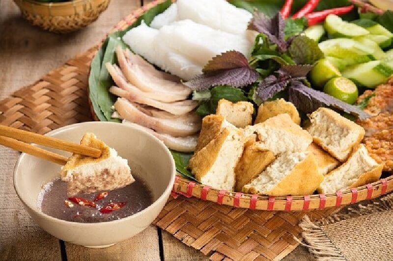 Bàn tay đang gắp bún và các topping để chấm mắm tôm