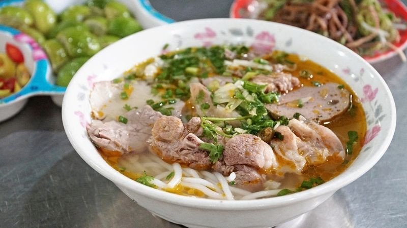 Bát bún bò Huế được trình bày đẹp mắt với hành ngò và các loại rau sống tươi xanh