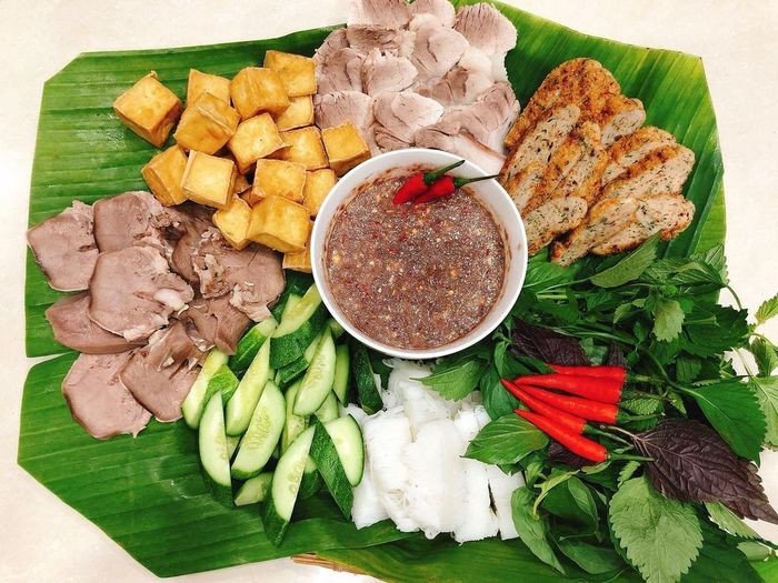 Đầu bếp đang nhẹ nhàng sắp xếp các thành phần trên mẹt bún đậu mắm tôm