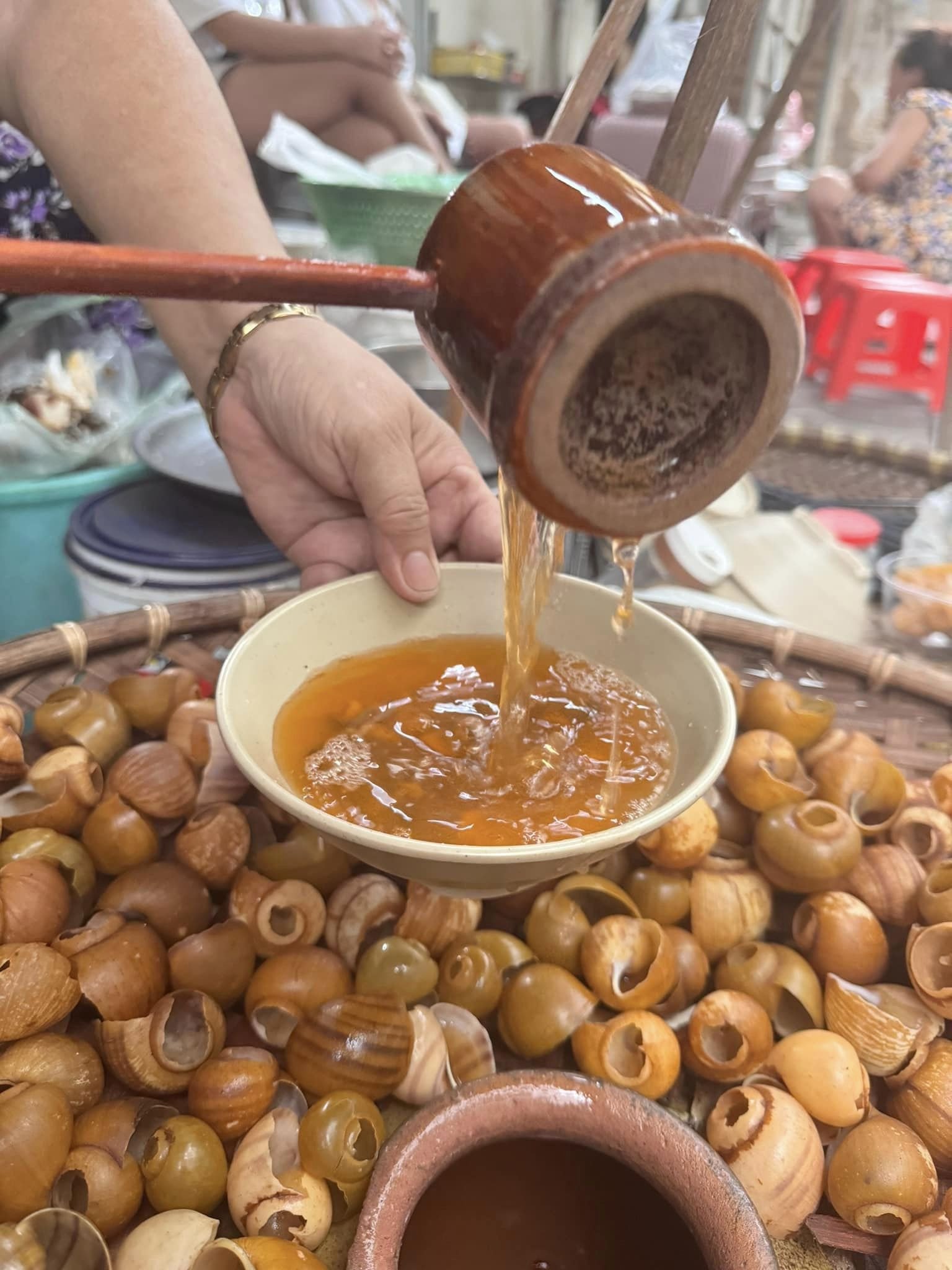 Hai bát bún ốc nguội bày biện trên gánh hàng với các loại ốc khác nhau
