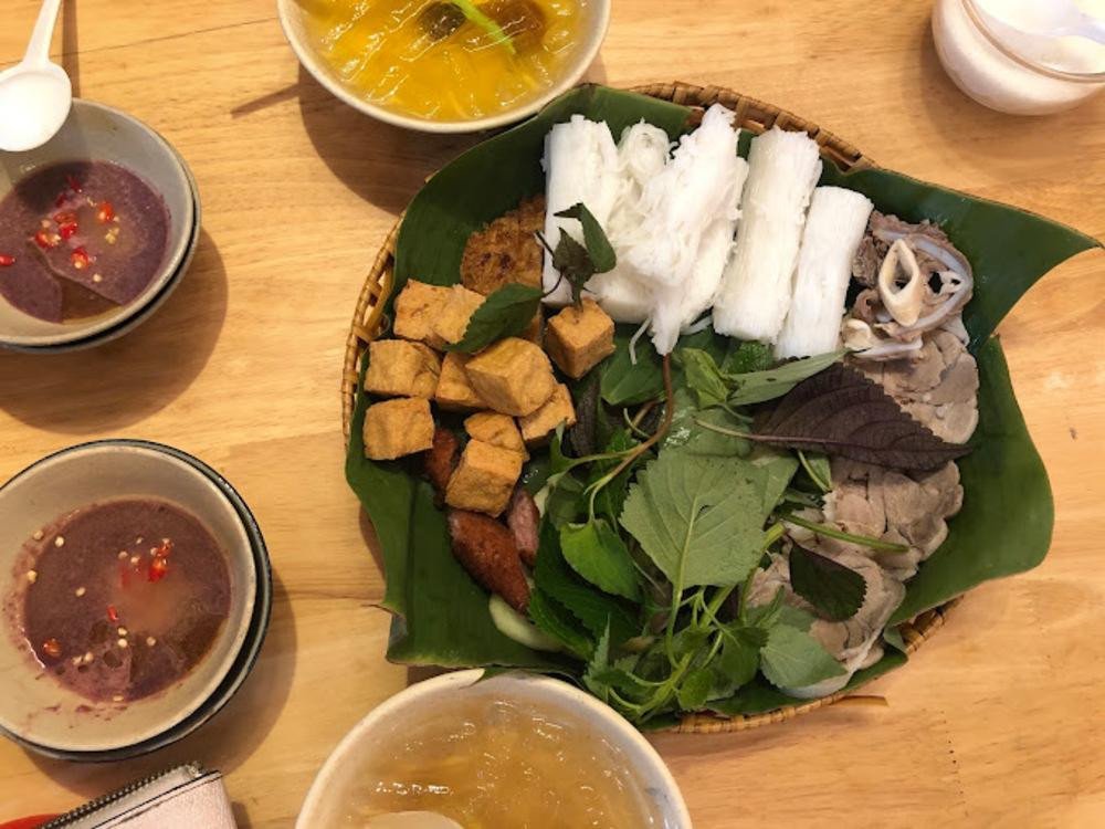 Hình ảnh cận cảnh các loại topping đa dạng như nem rán, chả cốm trong một mẹt bún đậu