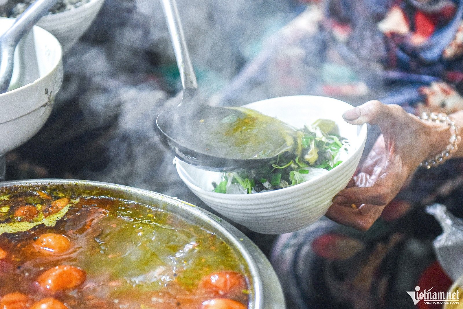Hình ảnh thực khách đang thưởng thức bát bún ốc tại một quán ăn đông đúc