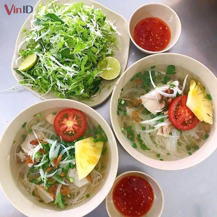 Một tô bún cá Nha Trang đầy đủ topping với chả cá hấp và chả chiên