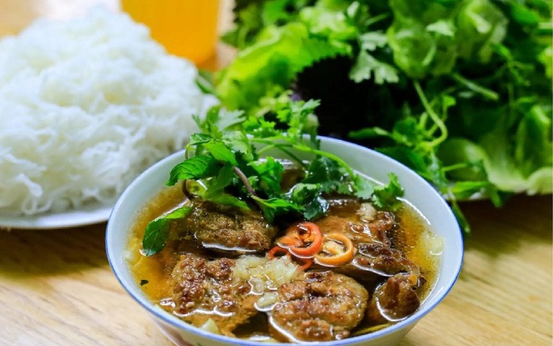Tô nước chấm sóng sánh, nổi bật với cà rốt, đu đủ muối giòn giòn và miếng chả nướng vàng ươm