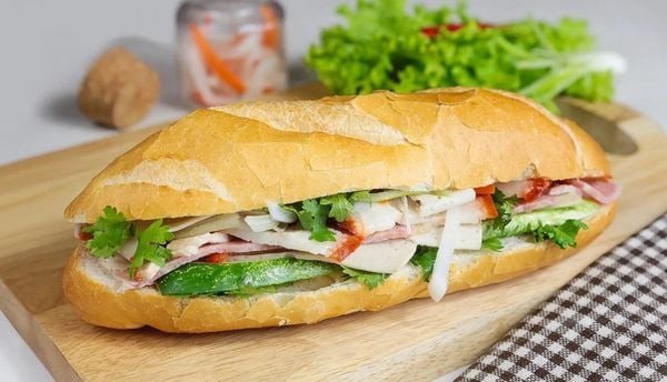 Bánh mì thịt nguội cắt lát sẵn sàng thưởng thức, với pate, chả và rau tươi