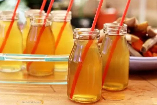 Cảnh một nồi nước mía lau đang được nấu với các nguyên liệu như mía, rễ tranh, lá dứa