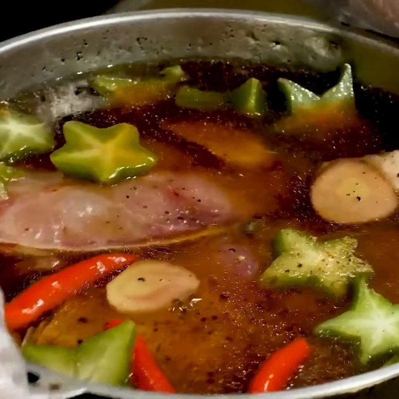 Chan nước kho đậm đà vào nồi cá kho riềng đang xếp