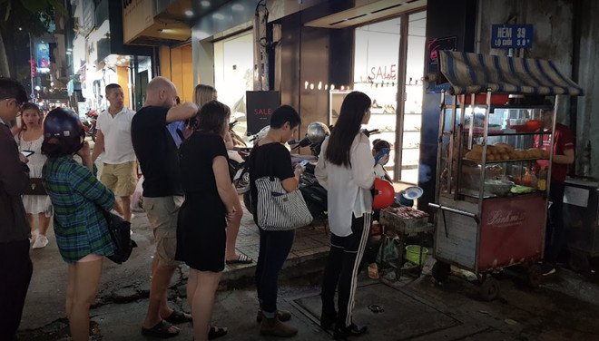 Người đàn ông đang chuẩn bị bánh mì thịt nướng tại xe bánh mì Nguyễn Trãi